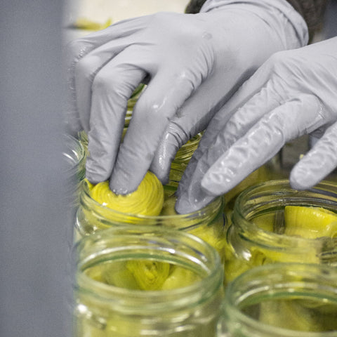 Alcachofas colocadas a mano dentro del tarro de cristal