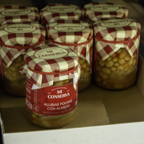 Tarros de pochas con almejas recién envasados en el obrador
